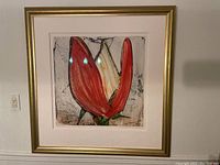 Framed color lithograph depicting a red tulip with a green stem and an abstract background, mounted with a white mat and enclosed in a gold frame.