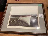 Full view of framed lithograph featuring a white skiff in a grassy shoreline scene, showing overall condition and framing.
