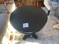 Overhead view showing the black round tabletop with small scratches and the numbered lot tag.