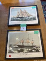 Two of the framed clipper ship prints from the set are shown from above on a wooden table.