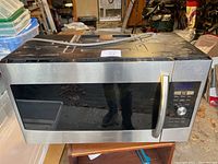 Front view of the Samsung microwave showing stainless steel and black glass door with handle and control panel.