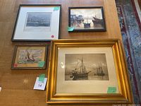 Front view of four framed ship-themed artworks on a wooden table.
