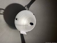 Close-up photo of the frosted glass bowl light shade from below showing fluted details and a central decorative finial.