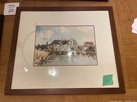 Dark brown framed watercolour of a house by water with marsh grasses