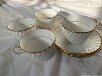 Four white Aynsley tea cups and four matching saucers with gold rims, showing swirl pattern and overall lot