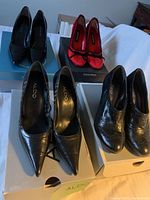 Three pairs of large women's heels arranged on shoe boxes including ALDO, Nine West, and textured ankle boots