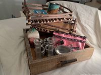 Wooden tray with miscellaneous desk items inside including glass shakers, apple container, pouch, metal dish, and twig rack.