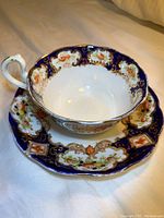 Royal Albert Alhambra tea cup and saucer set, showing inside of cup and saucer with intricate floral and gold detailing on cobalt blue and white bone china.
