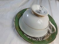 Tea cup shown upside down revealing the Royal Grafton maker's mark and vintage year 1942. The saucer underneath shows green and gold detailing.