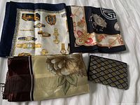 Three vintage scarves and one small clutch arranged flat on fabric surface.