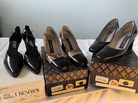 Three pairs of vintage women's heels size 37 displayed on their original boxes. Left pair is black patent leather with pointed toe and ankle strap, center pair is snakeskin pattern with black toe cap, right pair is solid black heels.