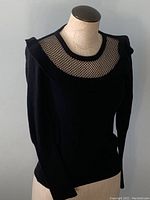 Front angled view of the black Sonia Rykiel vintage sweater showing mesh detail around upper chest and shoulder ruffles