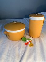 Photo of yellow Sunfrost Therm-o-ware pitcher, ice bucket, and four colored measuring spoons on white background.