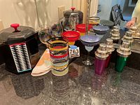 Overview of barware set including colorful glasses, metallic cocktail shakers, and hexagonal black ice bucket with geometric design