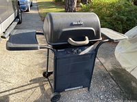 Full view of Char-Broil Quickset gas grill showing black body, wheels, side shelves, and lid with handle.