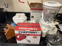 Side view of Hamilton Beach BlenderChef box and kitchen items including Chefman hand mixer box, knife block, and blender.
