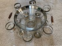 Overall top-down view of punch bowl set showing the arrangement of seven cups around the bowl and the metal frame with wooden handles.