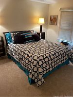 Front angle of queen bed with bedding, showing headboard, comforter, pillows and bedskirt.