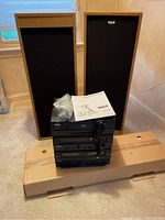 Full view of the RCA audio system components stacked with speakers in the background and the original box below.