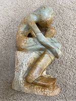 Top angled view of the marble seated thinker sculpture showing the entire figure and base.