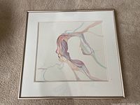 Framed watercolor artwork showing abstract colorful profile of a woman with translucent flowing lines.