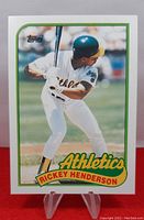 Front of 1989 Topps Traded Rickey Henderson baseball card showing batting image and Athletics branding.