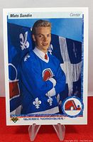 Front side of 1990-91 Upper Deck Mats Sundin rookie card with player portrait, team logo and blue background.