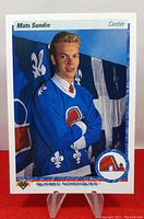 Front of the Mats Sundin rookie card showing the player in Quebec Nordiques jersey with background flags.