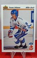 Front of 1991-92 Upper Deck Teemu Selanne rookie hockey card, showing player in white Finnish national team uniform with helmet and stick.
