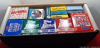 Top view of sealed trading card packs in a box showing various brands and years.