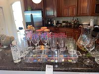 Wide view of all glassware items displayed on kitchen counter including pitcher, wine glasses, water glasses, and serving tray.