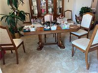 View of the wooden dining table with four matching upholstered chairs around it, showing the table surface with various small containers and miscellaneous items on top (contents not included).