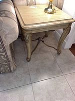 Front-side view of solid wood end table placed beside sofa with lamp on top.