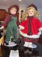 Photo of two Heritage Mint dolls standing side by side on display stands, showing full outfits and tags