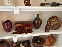 Full view of ceramic vase, wooden box, plate, wooden flower bowl, carved wooden spheres, and vine accent on shelf