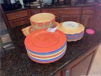 Stack of dinner plates, salad plates, and the salad bowl on top, showing warm red to yellow-orange color tones with glaze finish.