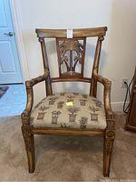 Front view of vintage wooden armchair with palm tree carving and palm tree patterned fabric seat.