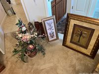 Two framed wall art pieces and faux flower arrangement on floor