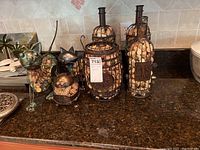 Seven decorative items: 3 wine bottle-shaped wire cages filled with corks, 4 cork-bodied cat figurines with metal detailing