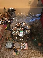 Full view of the bar accessories showing eight stainless steel cocktail glasses on a metal tray, an ice bucket, assorted glassware, coasters and small bar items.