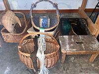 Photo showing several wicker baskets, a small wooden stool, and a black metal hanging basket rack in a garage setting.