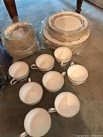 Stacked Aynsley China plates and cups on carpet.