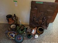 Various decorative items including ceramic duck figurines, assorted vessels in different styles and colors, and a large brown bas-relief wall art with figures and barrels.