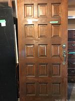 Front view of wooden panel door showing 12 raised sections and attached metal handle/lockset.