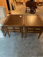 Two solid wood living room end tables with rectangular tops, decorative legs, and single drawers each, placed side by side on carpet.