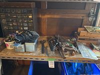 Wide view of table showing assorted tools, gloves, and hardware containers