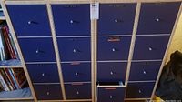Front view of two matching blue cabinets with eight drawers each, various labels visible on drawers