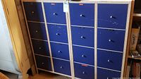 Full view of two matching blue metal cabinets next to each other, each with multiple drawers and metal knobs, showing scratches and wear.