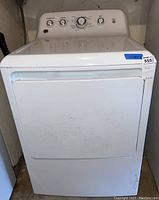 Front view of the white GE electric clothes dryer with door closed showing some dirt marks.