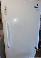 Front view of white GE upright freezer showing door, handle and overall exterior condition